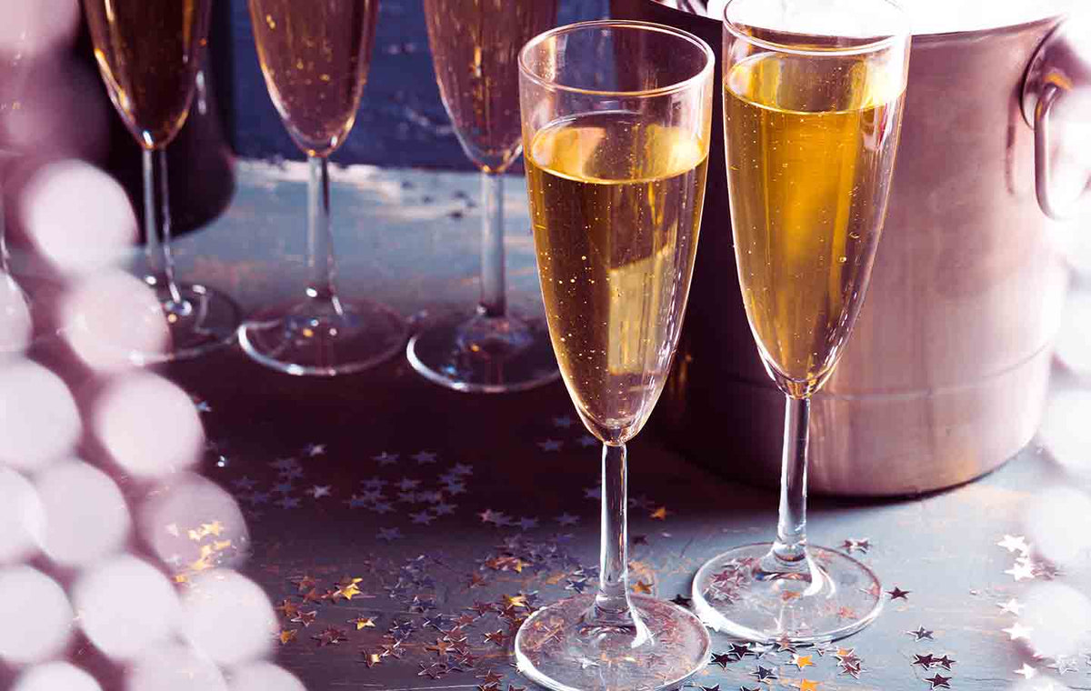 Close up of two champagne glasses on a table with silver star confetti.